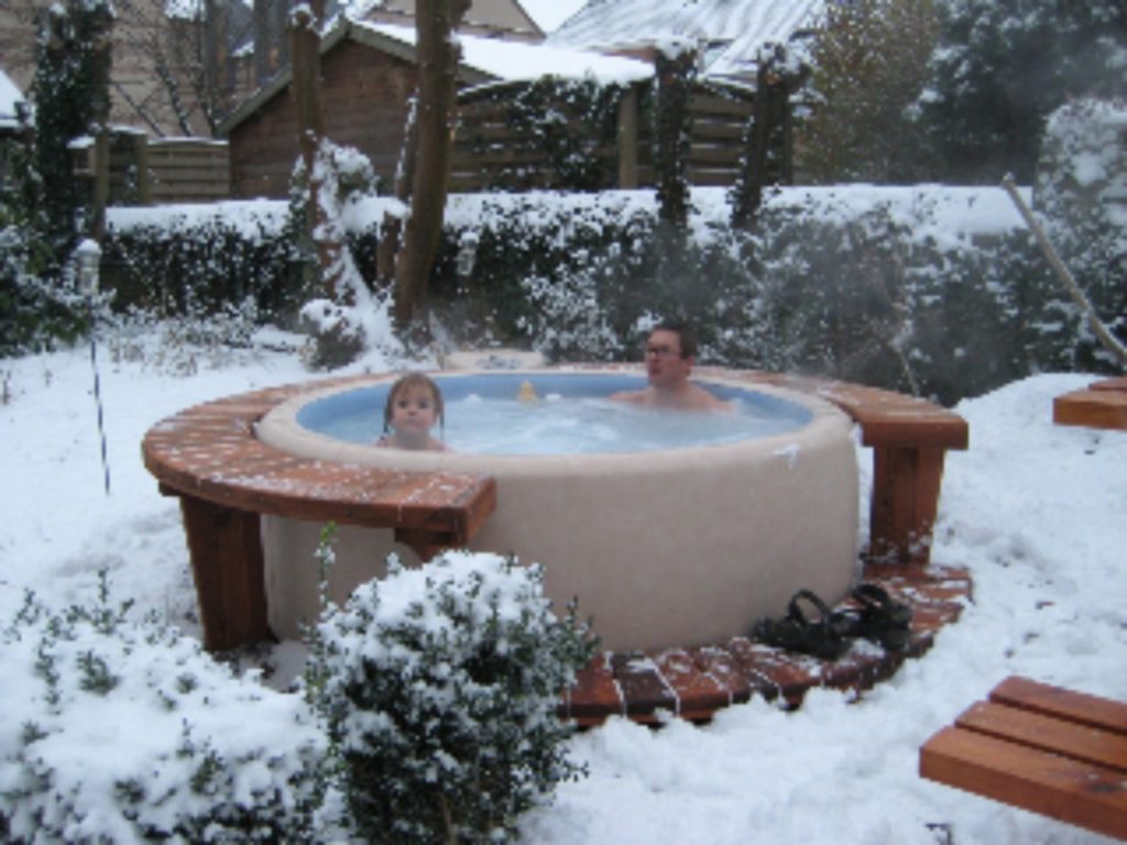 A man and a little girl enjoy their softub spa in winter