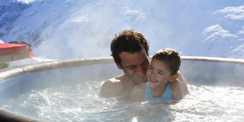 Ein kleines Mädchen und ihr Vater in einem Softub-Spa in den Bergen